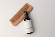 Wooden comb and bottle of scalp and hair care product on a light gray background